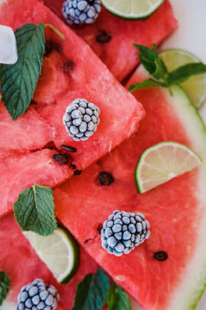 Watermelon slices, frozen blackberry and lime on a plate on white background. Top viewの写真素材