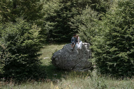 Stylish Romantic  couple on the big rock against the forestの写真素材