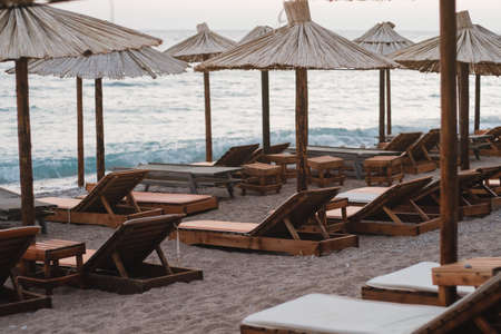 Empty beach with sun beds and straw umbrellas by the seaの写真素材