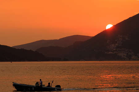 Yacht in the rays of the setting sun against the mountains background  in Mediterraneanの写真素材