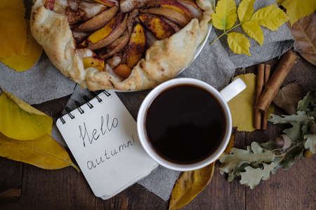 Diary Hello Autumn and Pie with apples, coffee. Dry leaves on a wooden table.の写真素材