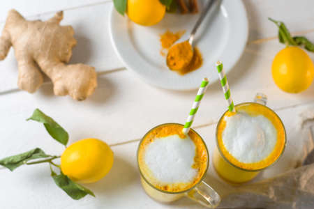 Top view of Turmeric latte or golden milk in glasses and lemons on a white table
の写真素材