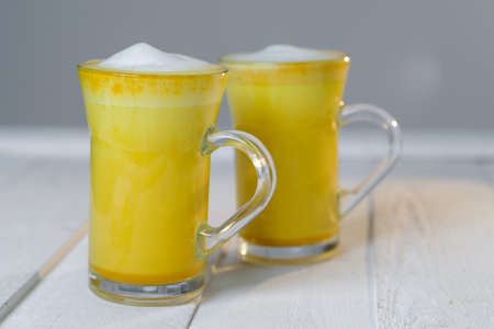 Turmeric latte or golden milk in glasses on a white tableの写真素材