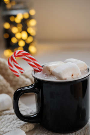 Cocoa with marshmallows and chocolate on a background of Christmas lightsの写真素材