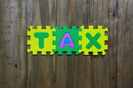 Letter puzzle block and word Tax with wood backgroundの写真素材