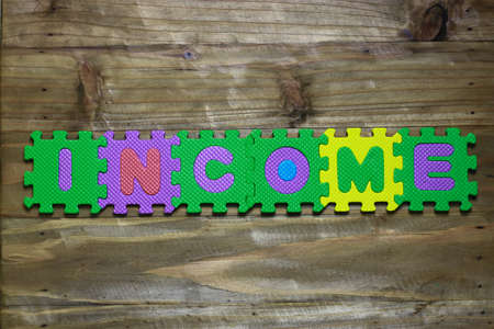 Letter puzzle block and word income with wood backgroundの写真素材