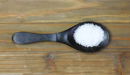 Salt in wooden ladle on wooden tableの写真素材