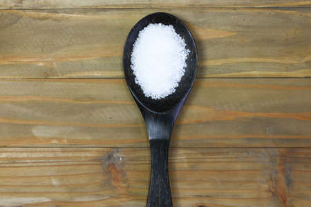 Salt in wooden ladle on wooden tableの写真素材