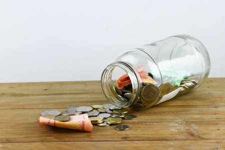 Money and glass container isolated on wooden table