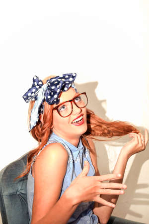 Young girl with glasses on smiles and plays with hair and the other hand faces camera  In her hair a...