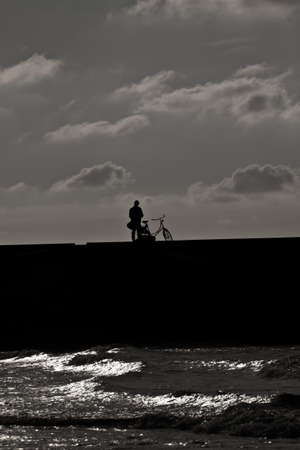 Person next to his or her bicycle on the pier, black   whiteの写真素材