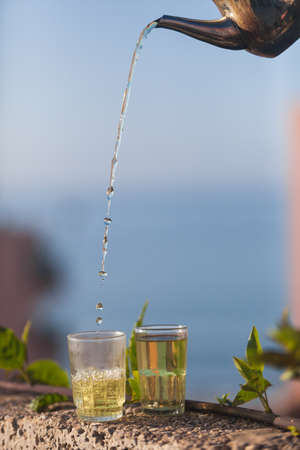 Moroccan green mint tea being poured into a glass.の写真素材