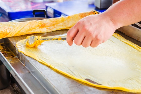 man making indian food by buttered flat bread roti in pan