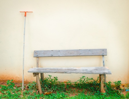 old outdoor wood bench and rake against the wallの写真素材