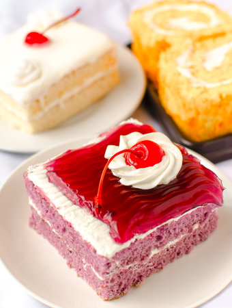 cake with mousse whipping cream and cherry on top. Shallow Depth of field with focus on the cherryの写真素材