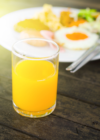 glass of orange juice and breakfast meal with soft sun light effectの写真素材