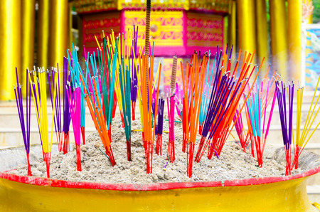 colorful of incense sticks burning in a golden pot at the templeの写真素材