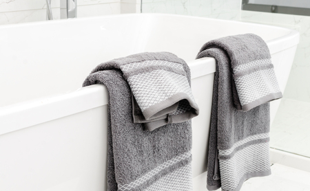 towels hanging on bathtub in bathroomの写真素材