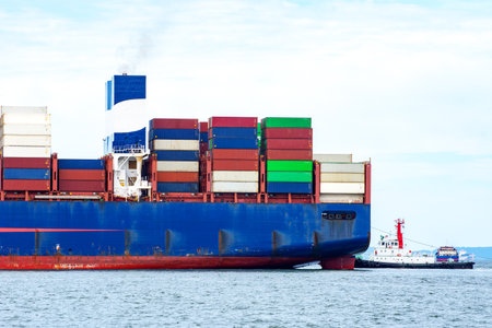 Container ship full capacity approaching the port by a tugboat occupying the port International Container ship loading, unloading at sea port, Freight Transportation, Shipping,  Vessel. Logistics, import export, Transportation. Global transport business.の写真素材
