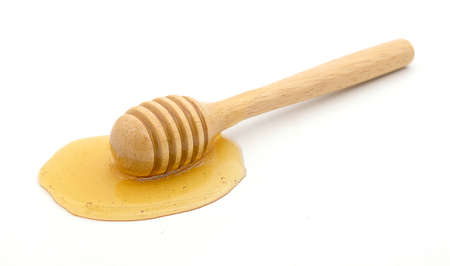 Wooden honey dipper with honey white backgroundの写真素材