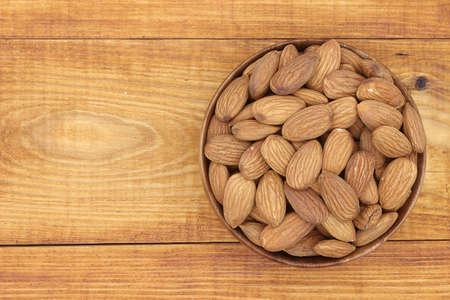 almonds  in bowl  on wood background copy space top viewの写真素材