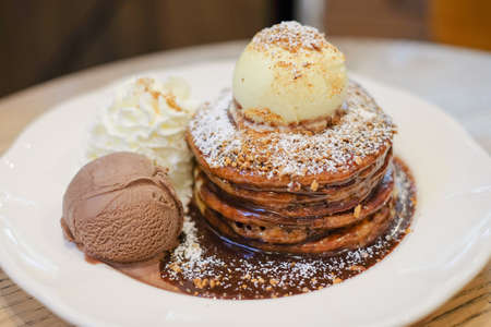 Pancake with almond, whipped cream and vanilla ice cream serve on white dish for dessert background.の写真素材