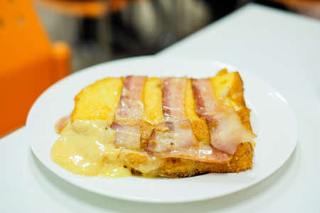 Homemade "Bacon and Ham put on bread with cheddar & mozzarella cheese" serve on white plate for food background or texture - breakfast concept.の写真素材