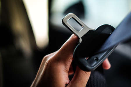 Hand of driver holding seat belt (safety belt) lock in car before driving - safety & secure concept.