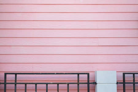 Pastel wooden wall for home with black steel fence.