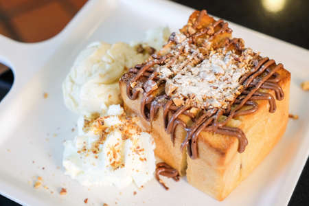 The toast bread topped with chocolate & almonds, whipped cream and vanilla ice cream serve on white dish for dessert background or texture.の写真素材