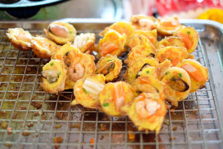 "mussels, shrimp, squid/octopus" in Takoyaki balls on metal grid - Japanese or Thai-style food background or texture.の写真素材