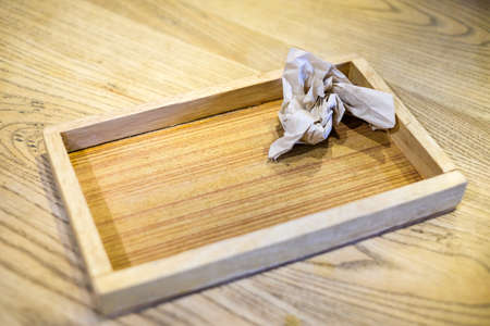 Handmade wooden tray with crumpled paper on the brown table for background or texture.の写真素材