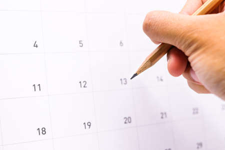 Hand holding pencil for writing information appointment on calendar (list to do/event in 2018) for activity background or texture.の写真素材