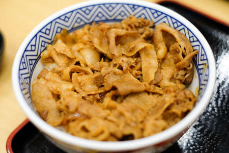 Rice with grilled pork teriyaki in the ceramic bowl under the black tray for japanese food background or texture.の写真素材