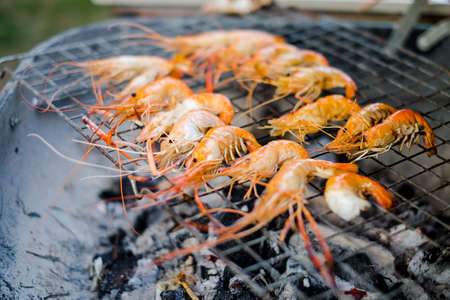Shrimp (seafood) burned or grilled with black charcoal on metal grid - party food & picnic concept in the summer.の写真素材