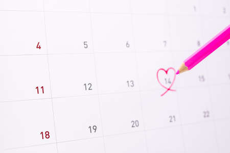 Pink crayon or pastel (wooden pencil) writing on 14 Feburary with pink heart on calender - Valentine's Day concept.の写真素材