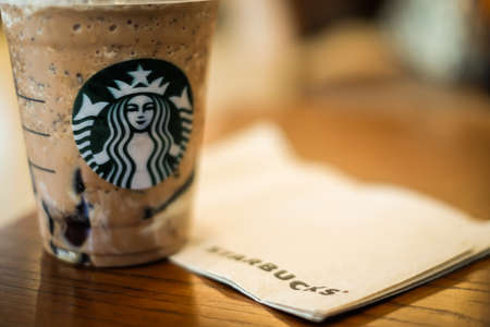 Bangkok, Thailand - January 30, 2018 :  Ice Twix Frappuccino (Cappuccino & Frappe) on brown table with tissue or paper & Starbucks coffee sign.のeditorial素材