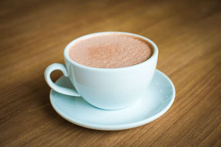 Cup of hot coffee (cappuccino or latte) decorated with milk forth on the surface serve on plate for...