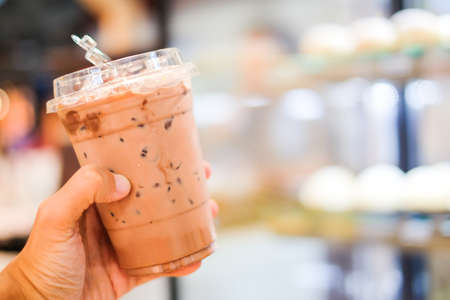 Hand holding ice cocoa or coffee (latte espresso or cappuccino) in plastic glass for relax & background or texture.の写真素材