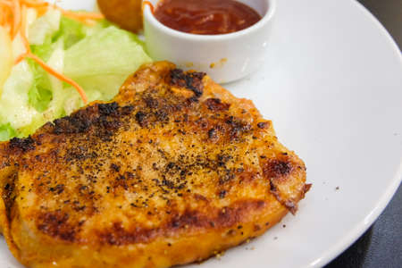 Pork steak marinated spicy and mashed potato (pig originating from English of Berkshire) with black pepper, sauce, pineapple and vegetable serve on white plate - food concept.の写真素材