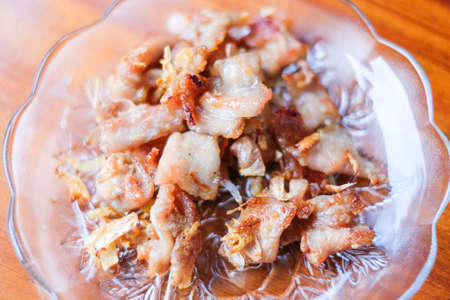 The garlic fried pork serve on white dish set on brown table - homemade food concept.の写真素材