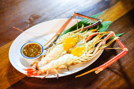 Grilled giant river prawn (shrimps) with spicy seafood set on wooden table at Ayutthaya Thailand - homemade food concept.の写真素材