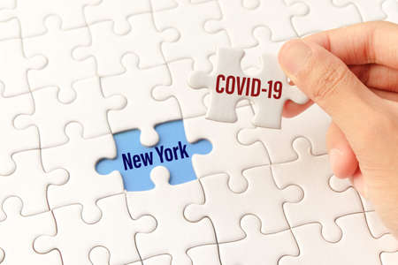 The COVID-19 word on white jigsaw puzzle go to replace New York word on blue gap - idea answer concept.の写真素材
