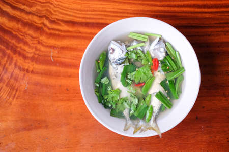 Spicy and sour soup mackerel serve on white bowl set on brown table - homemade food concept.の写真素材