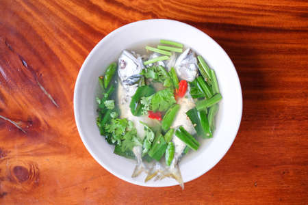 Spicy and sour soup mackerel serve on white bowl set on brown table - homemade food concept.の写真素材
