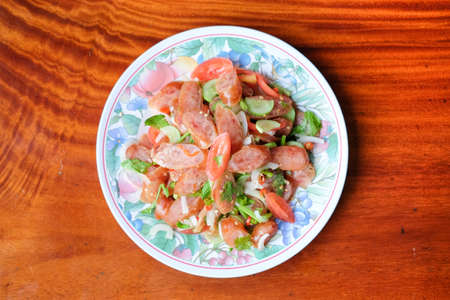 Chinese sausage spicy salad serve on white dish set on brown table - homemade food concept.の写真素材