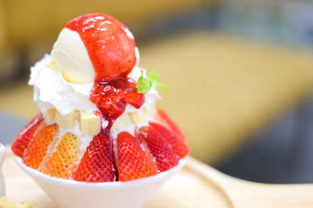 Strawberry kakigori (Japanese shaved ice dessert flavor with vanilla ice-cream) or bingsu (Korea dessert) serve on white bowl with strawberry sauce for sweet food background or texture.の写真素材