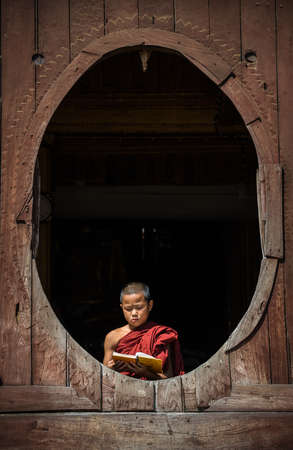 Myanmar novice reading the book in the Shwe-Yaunghwe monastery the big window temple in Myanmar.のeditorial素材