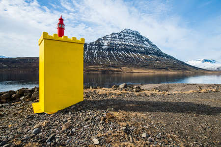 An iconic yellow lighthouse in front of Holmatindur mountain in Eskifjordur town of east Iceland.の写真素材