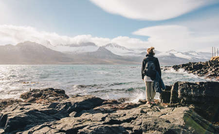 Tourist women with backpack and barefoot style standing near the coastal landscape in East region of Iceland.の写真素材
